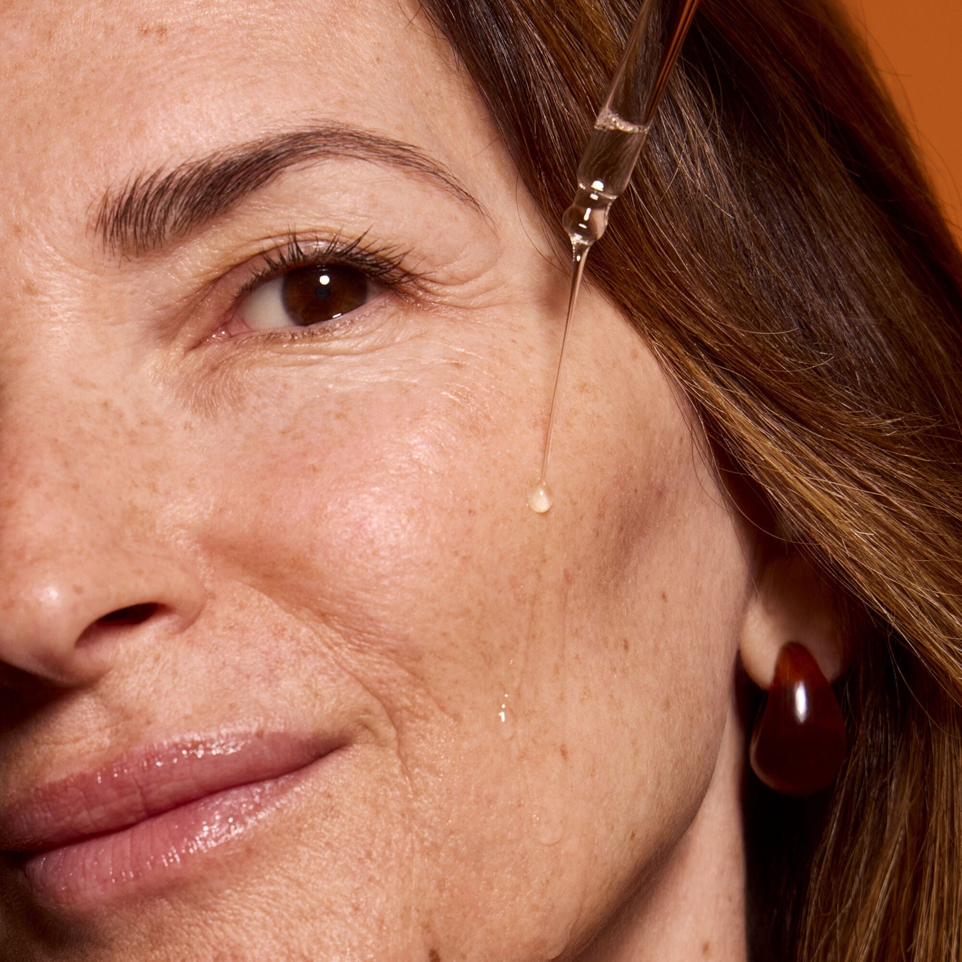 Close-up of a mature woman's face applying Bright Icon Vitamin C Serum 
