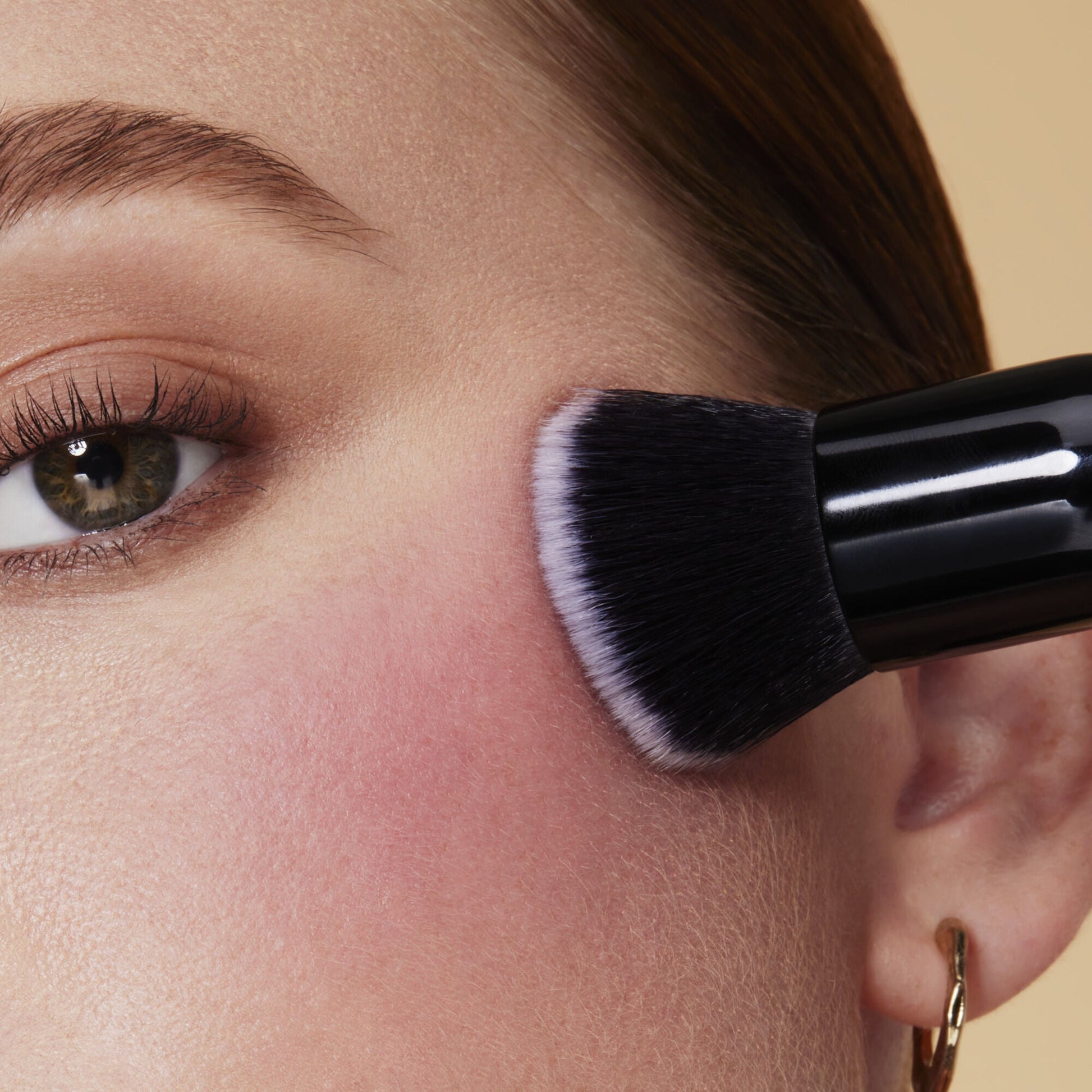 Woman applying Camo Liquid Blush with a brush on her cheek 